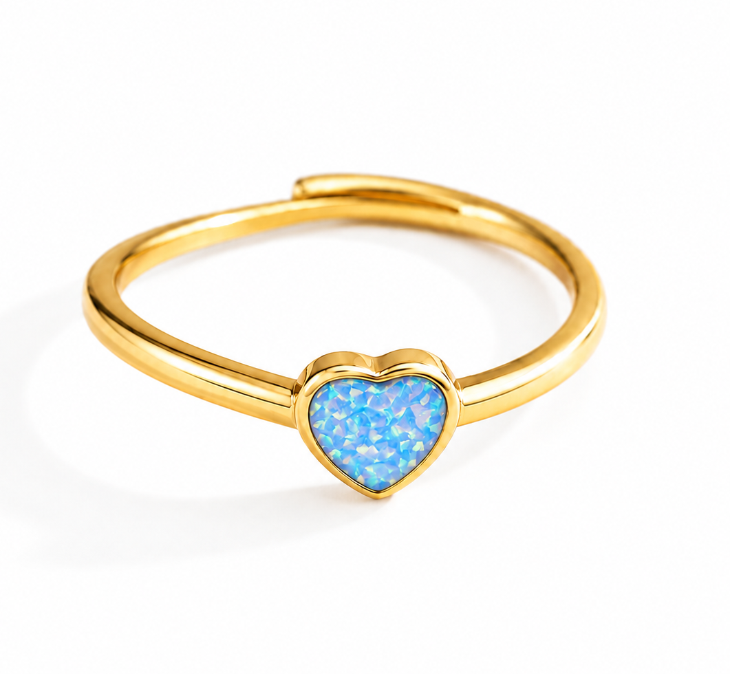 A gold-plated adjustable ring featuring a small, heart-shaped blue opal inlay, shown on a clean white background.