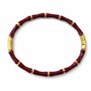 Red beaded bracelet with gold accents on a white background